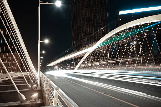 istock Arc bridge girder highway car light trails city night landscape 497964128