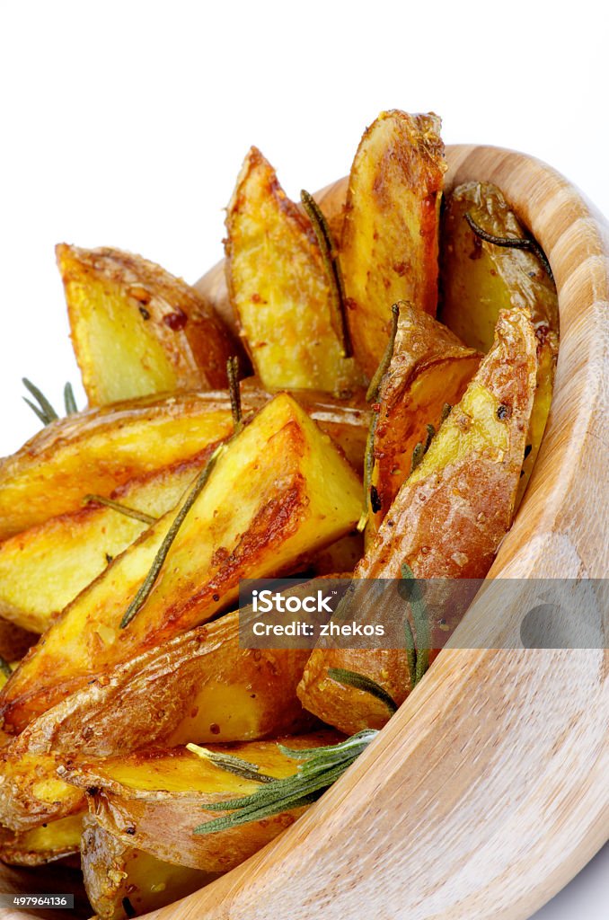 Roasted Potato Wedges Delicious Roasted Potato Wedges with Rosemary and Spices in Wooden Bowl Cross Section on White background 2015 Stock Photo