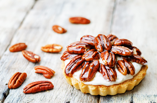 honey pecan tartlet on a white wood background. toning. selective Focus