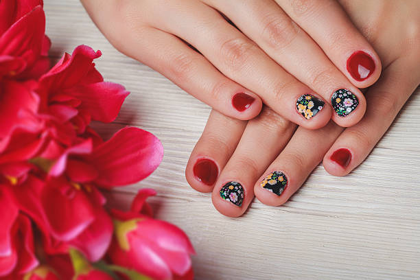 istock Red nail art with printed flowers on wooden background 497965728