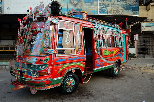 Karachi, Pakistan - February 22, 2015: An ornately painted and decorated passenger minibus stands on a side street in Karachi's Saddar district. Pakistani bus and truck drivers take great pride in decorating their vehicles using professional artists and craftsmen in a trade that has come to be called 'truck art.' Note the art consists not only of colors but also intricate panels and motifs.