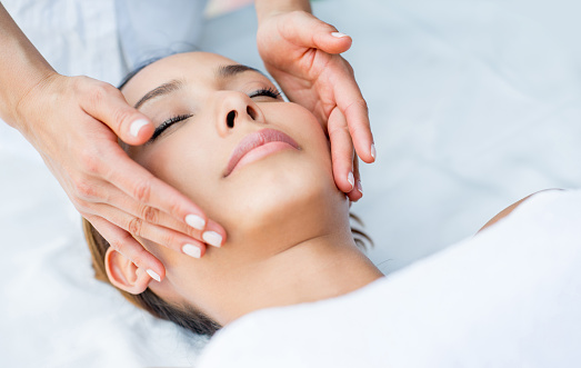 Beautiful Asian woman getting a facial and relaxing at the spa