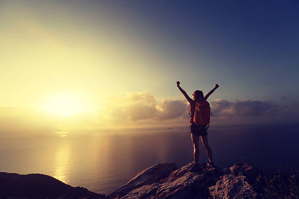 istock cheering young woman backpacker at sunrise seaside mountain peak 497971226