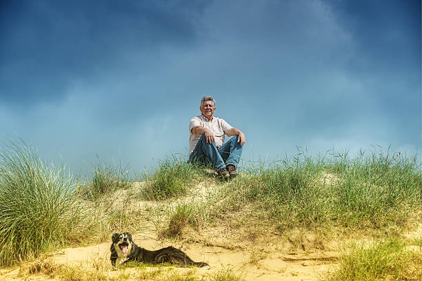 istock Man and dog, sitting/lying in sand dunes 497973211
