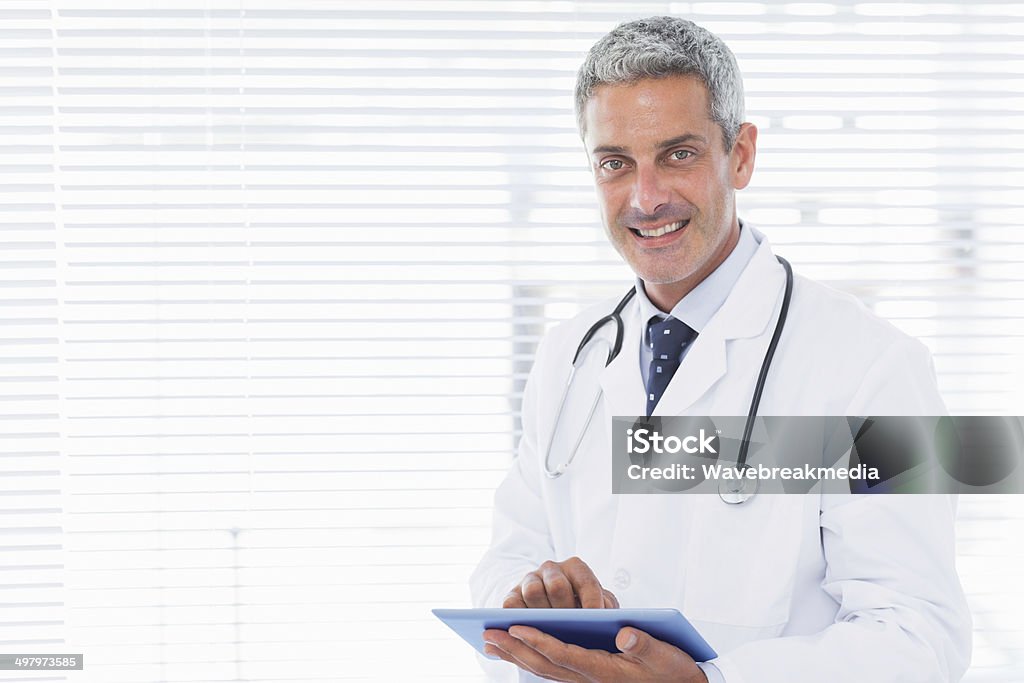 Smiling doctor using tablet pc Smiling doctor using tablet pc in medical office 30-39 Years Stock Photo