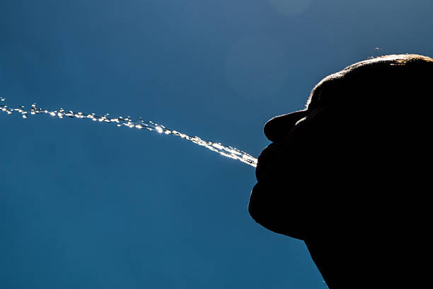 Playing with water on a hot summer day, the man is spitting water forward and upwards.