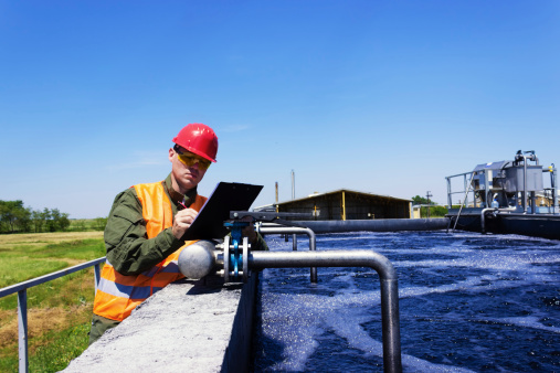 Worker inspecting valve for filtering water. Focus on Valve. Copy space available.