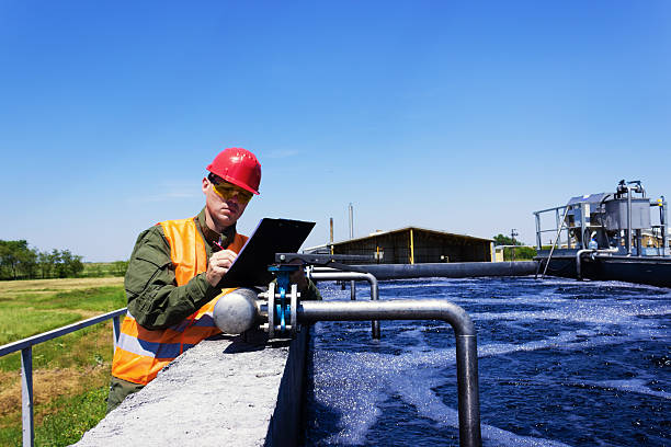 Worker inspecting valve Worker inspecting valve for filtering water. Focus on Valve. Copy space available. sewage treatment plant stock pictures, royalty-free photos & images