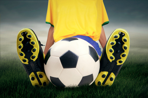 Soccer player take a rest while sitting on grass with a soccer ball