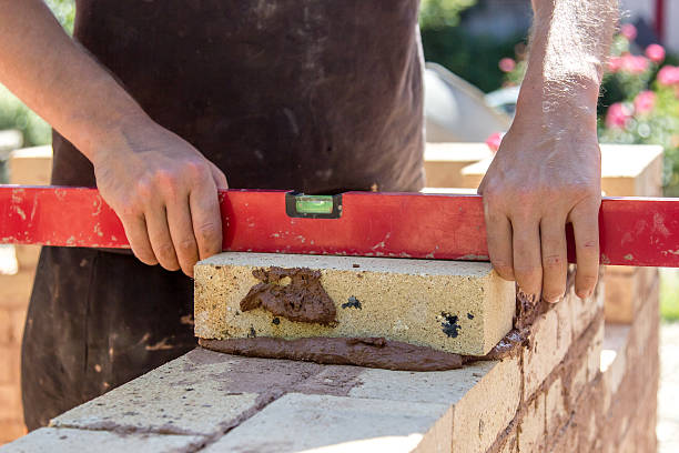 Leveling a brick worker leveling a brick while constructing a brick wall tehnical stock pictures, royalty-free photos & images