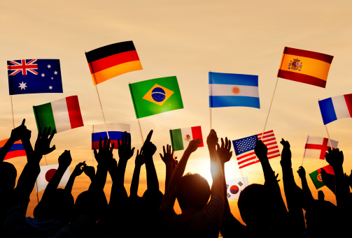 Silhouetted people holding various country flags