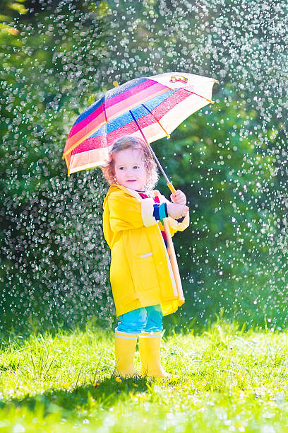 istock Funny toddler with umbrella playing in the rain 497979297