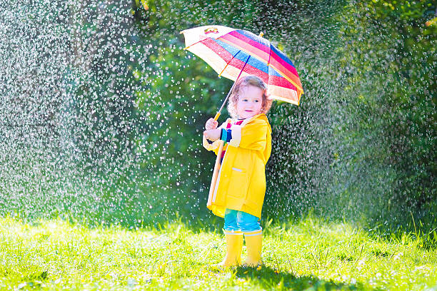 istock Funny toddler with umbrella playing in the rain 497979479