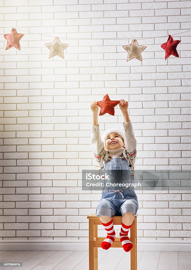 child hangs the stars Christmas Eve! A small child hangs the stars in garland. 2015 Stock Photo