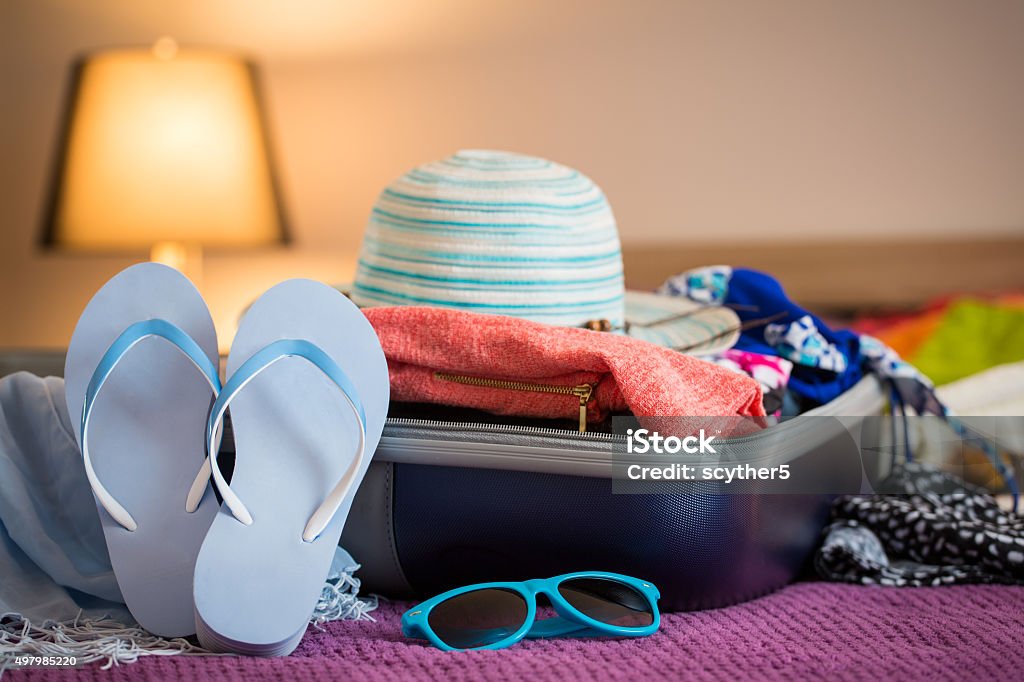 Open suitcase on bed Open suitcase with clothing in the bedroom. Summer holiday concept. Packing Stock Photo