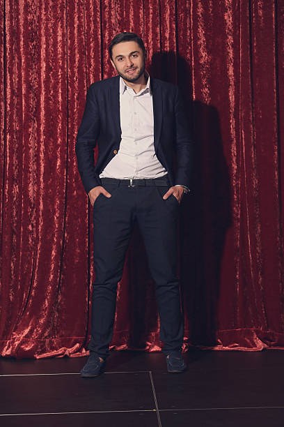 istock Young handsome man in black suit standing against background of 497986106