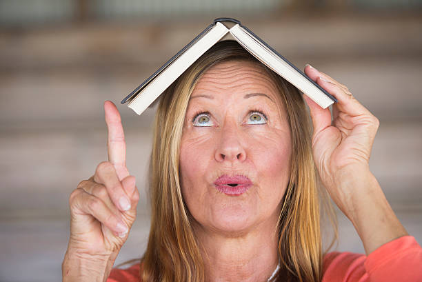 istock Mature woman with book on head and idea 497991846