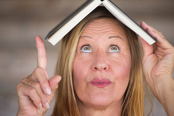 istock Portrait smart woman with book on head 497991982