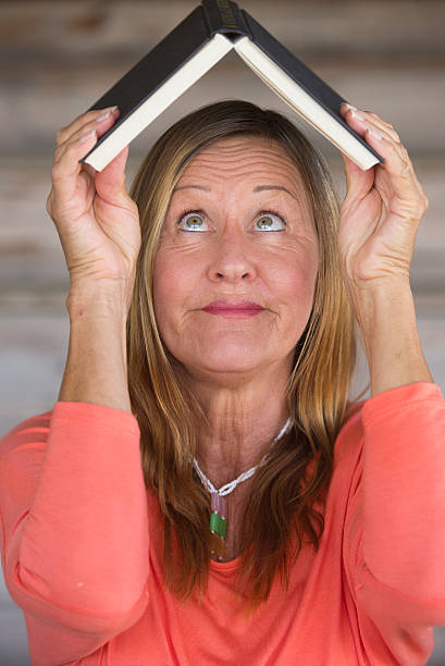 istock Portrait smart happy woman with book on head 497992310
