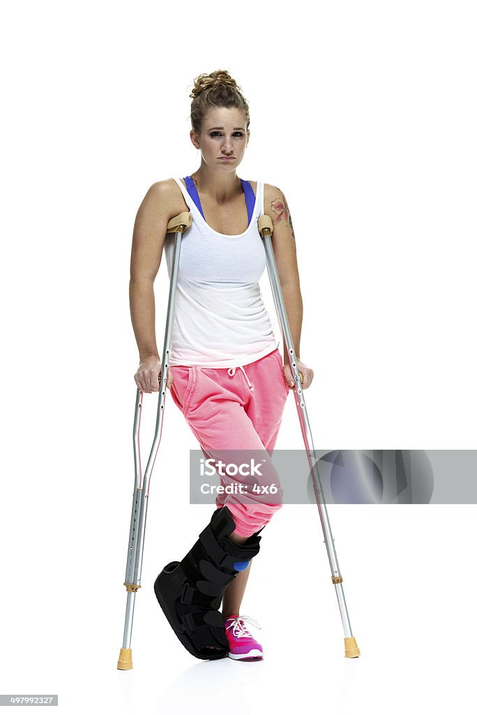 Woman stnding with crutches & looking at camera Woman stnding with crutches & looking at camerahttp://www.twodozendesign.info/i/1.png Leg Brace Stock Photo