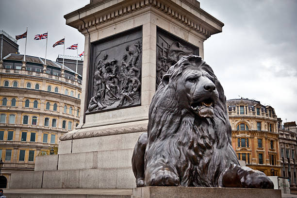 Bronze Lion at Trafalger Square with Union Jack flags flying in the background.