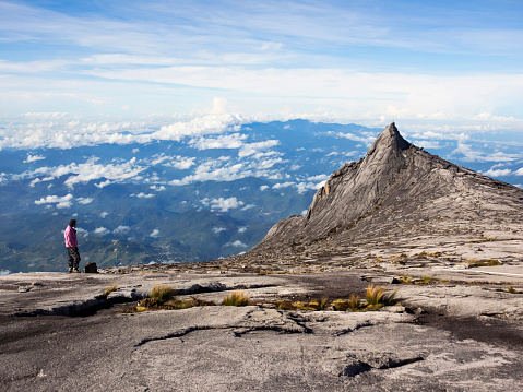 Kinabalu Park, Sabah, Malaysia - May 19, 2014: Unrecognizable hiker staring at the scenery at the top of Mount Kinabalu, the highest peak in the Malay Archipelago, on May 19, 2014, in Sabah, East Malaysia.
