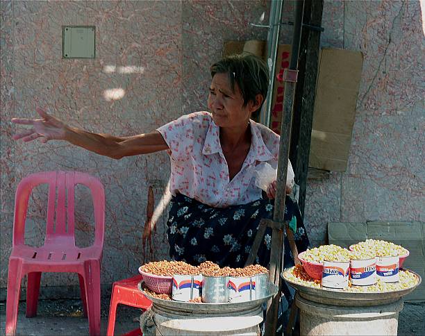 Yangon, Myanmar - December 20, 2013: Old burmese woman selling nuts on the street, Downtown Yangon