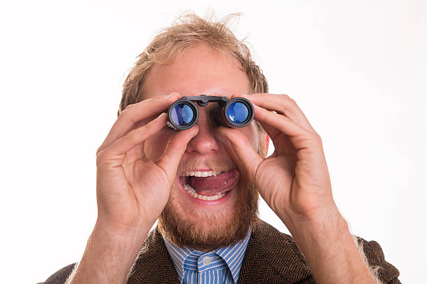 Pervert voyeur man watching someone through binoculars stock photo