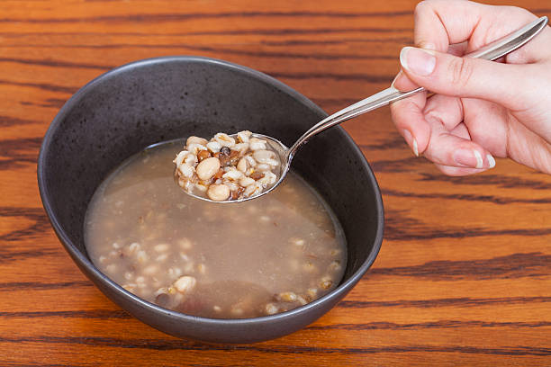 hand holds tablespoon with beans soup over bowl hand holds tablespoon with beans soup over ceramic bowl on wooden table soup lentil healthy eating dishware stock pictures, royalty-free photos & images