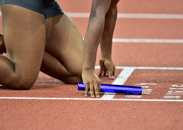 sportler mit baton konzentriert sich vor beginn staffel - starting line running sprinting alertness stock-fotos und bilder