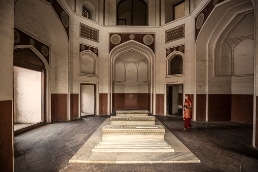 Delhi, India - September 18, 2015: Indian woman visiting Humayun's tomb. A fine example of persian styles of Islamic architecture it is World Heritage site by UNESCO. This building is one of the best preserved Mughal monuments. The construction was finished in 1572. No sepulcher in India contains such a high number of tombs of the Mughal emperors.