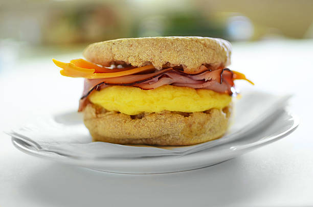 Egg, ham and cheese on whole wheat English muffin Scrambled egg, Black Forest ham and cheddar cheese on a whole wheat English muffin english muffin stock pictures, royalty-free photos & images
