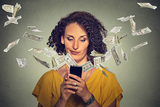 istock Annoyed woman using smartphone dollar bills flying away 498027898