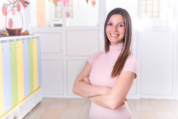istock Young Female Preschool Teacher Standing in Hall 498027904
