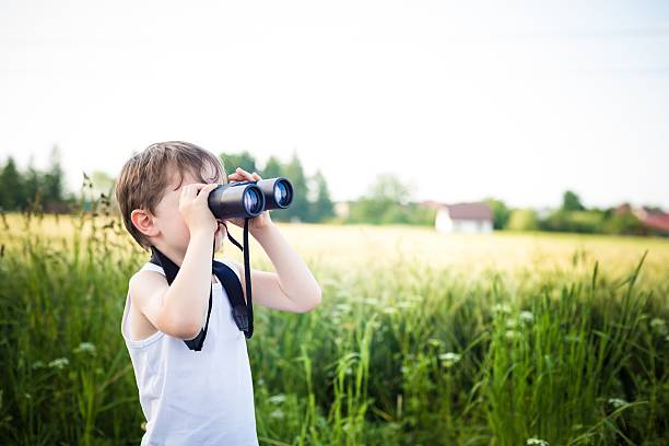 istock little boy in a field looking through binoculars 498028317