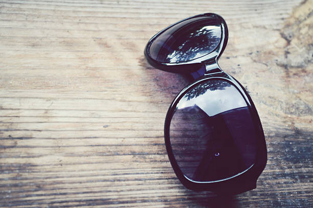 istock Black sunglasses with violet lenses on a wooden table closeup 498048023