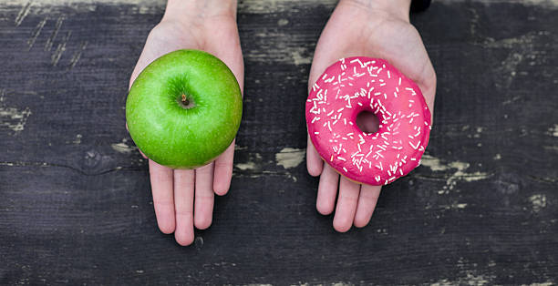 Choosing between apple and doughnut Choosing between apple and doughnut toughness stock pictures, royalty-free photos & images