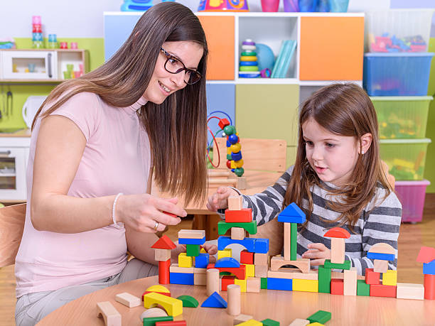 istock Kindergarten Teacher Building Castle With Toy Blocks 498050208