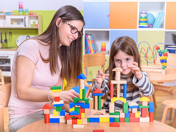 istock Happy Kid With Kindergarten Teacher Plays with Building Blocks 498053110