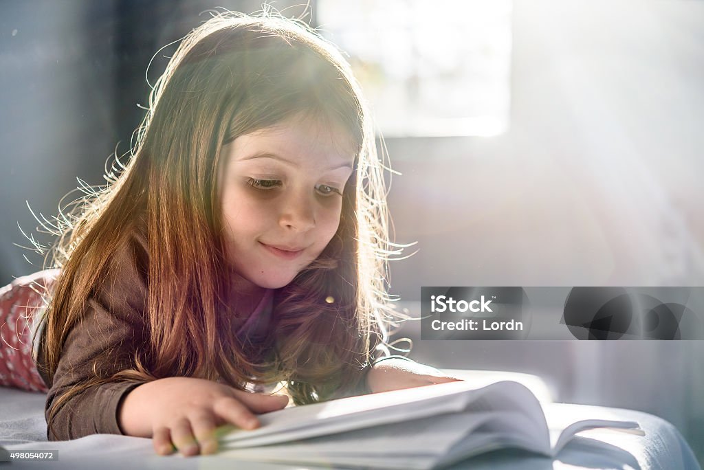 Cute Girl Reading a Book at Home Child Stock Photo