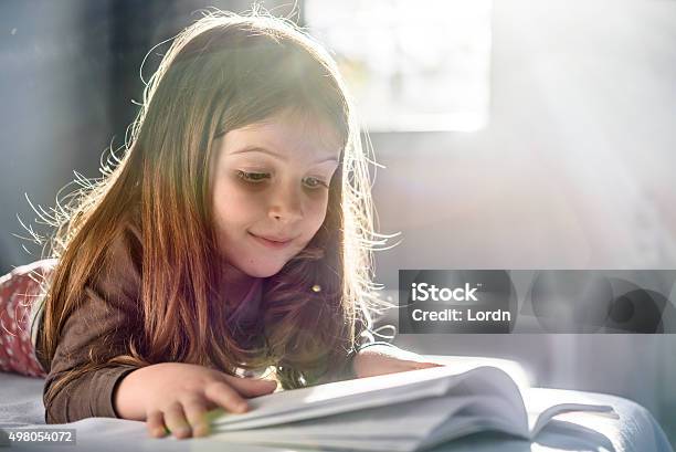Cute Girl Reading A Book At Home Stock Photo - Download Image Now - Child, Picture Book, Reading