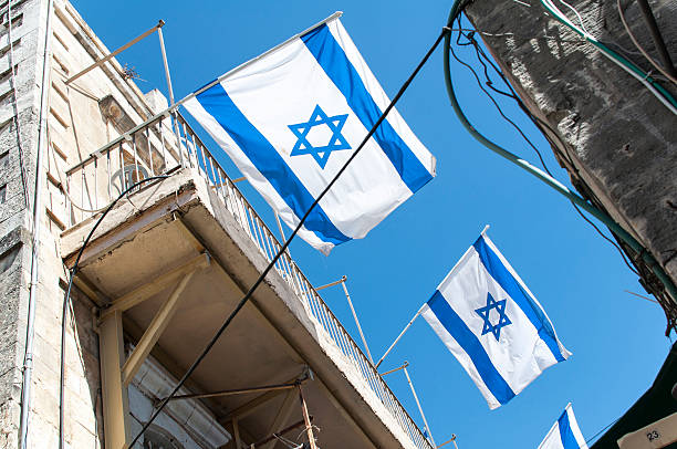 istock Israeli flag in street with blue sky 498054190