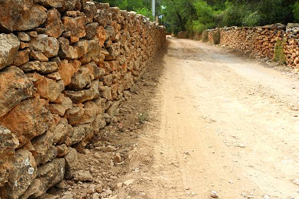istock masonry stone wall fence around sand soil track 498054752