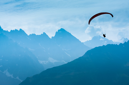 Paraglide shadow figure over Alps peaks