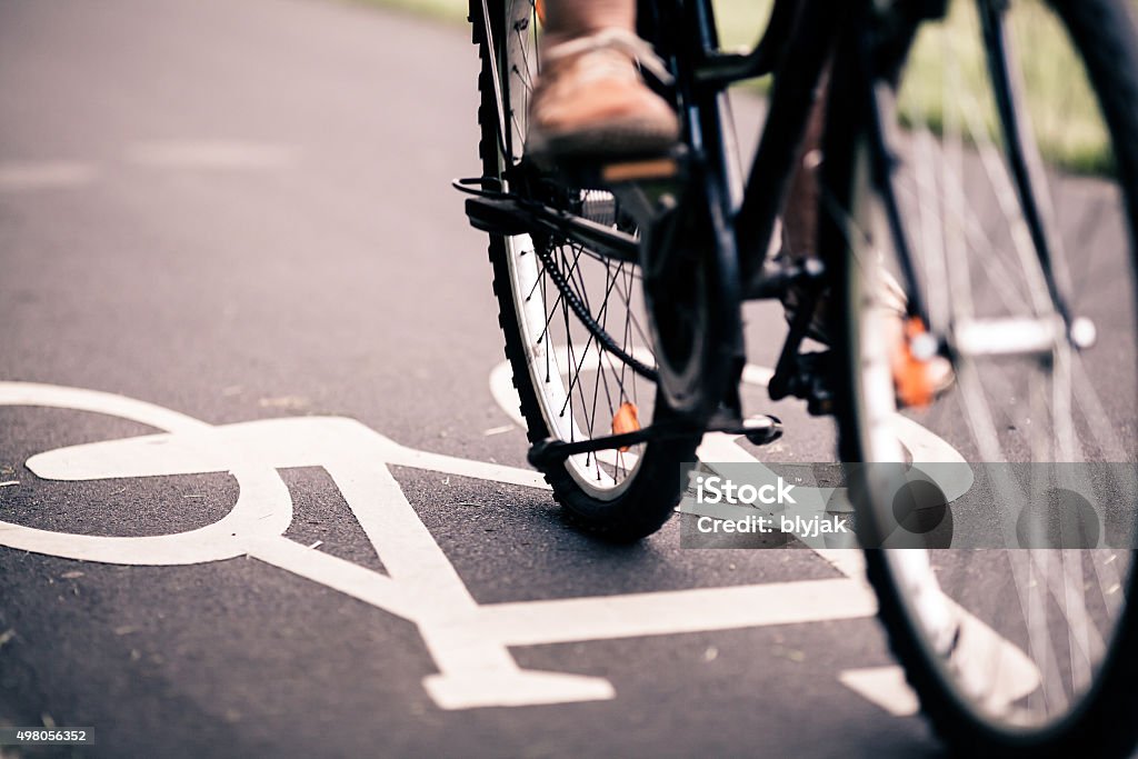 City bicycle riding on bike path City bicycle riding on bike path, alternative ecological transportation. Commute on bicycle in urban environment, asphalt gray bike lane with bicycle markings Cycling Stock Photo