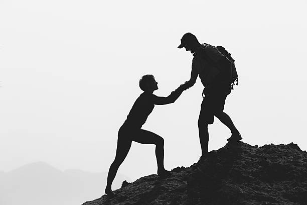 istock Teamwork couple hiking climbing helping hand 498057158
