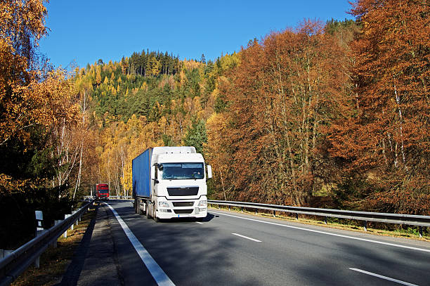 istock Trucks on the road in a wooded valley 498058450