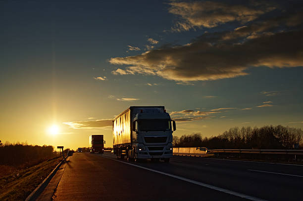 istock Trucks on asphalt highway in a rural landscape at sunset. 498059396