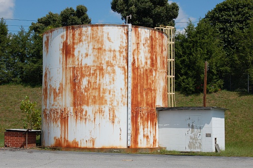 Rusted water storage tank with pump house.  There is also a meauring device to tell how full the tank is.