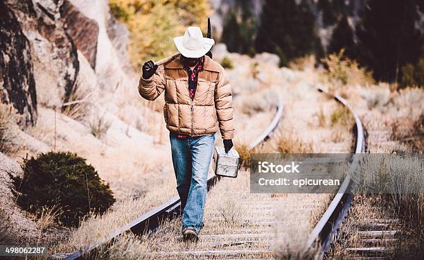 Man Walks Along Overgrown Western Railroad Tracks Carrying Tools Stock Photo - Download Image Now